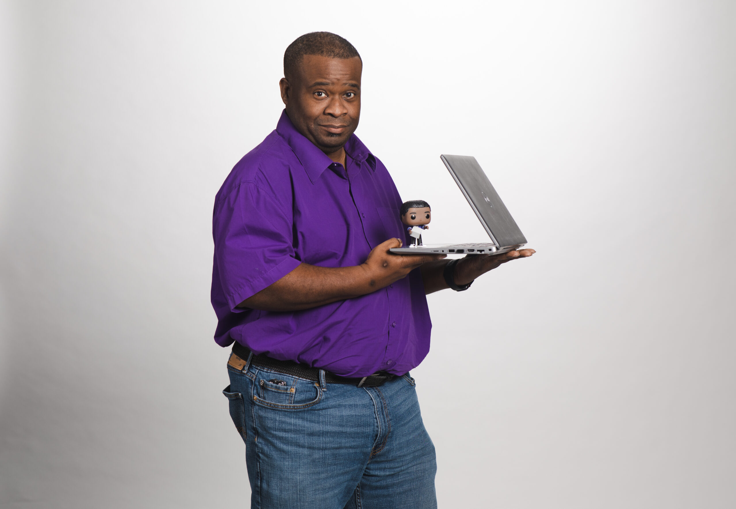 Picture of damian holding a laptop with a miniture representation of himself